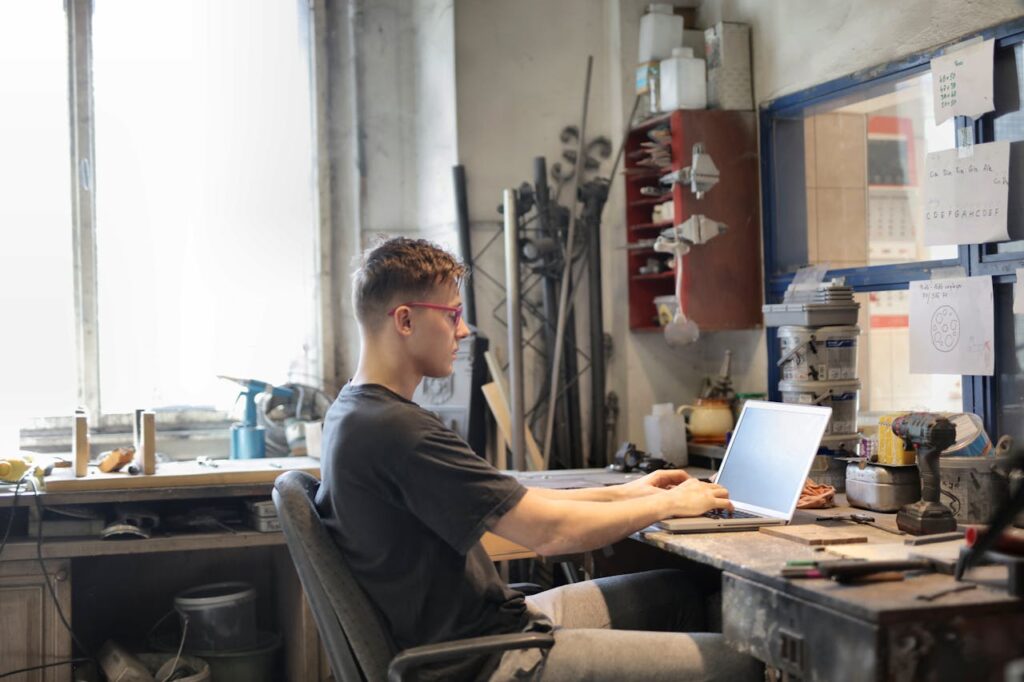 Focused man working on laptop in workshop