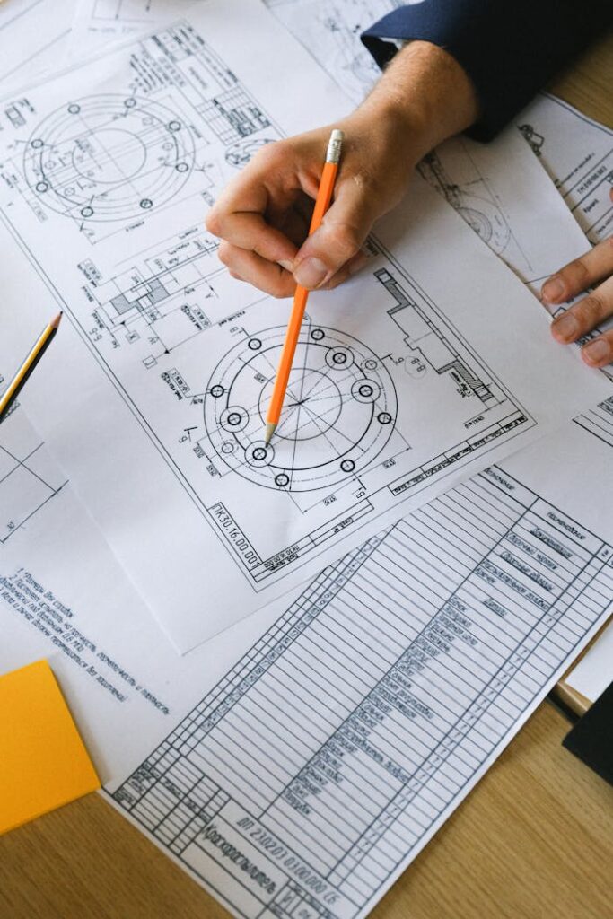 From above of crop anonymous male with pencil in hand examining information on paper at table